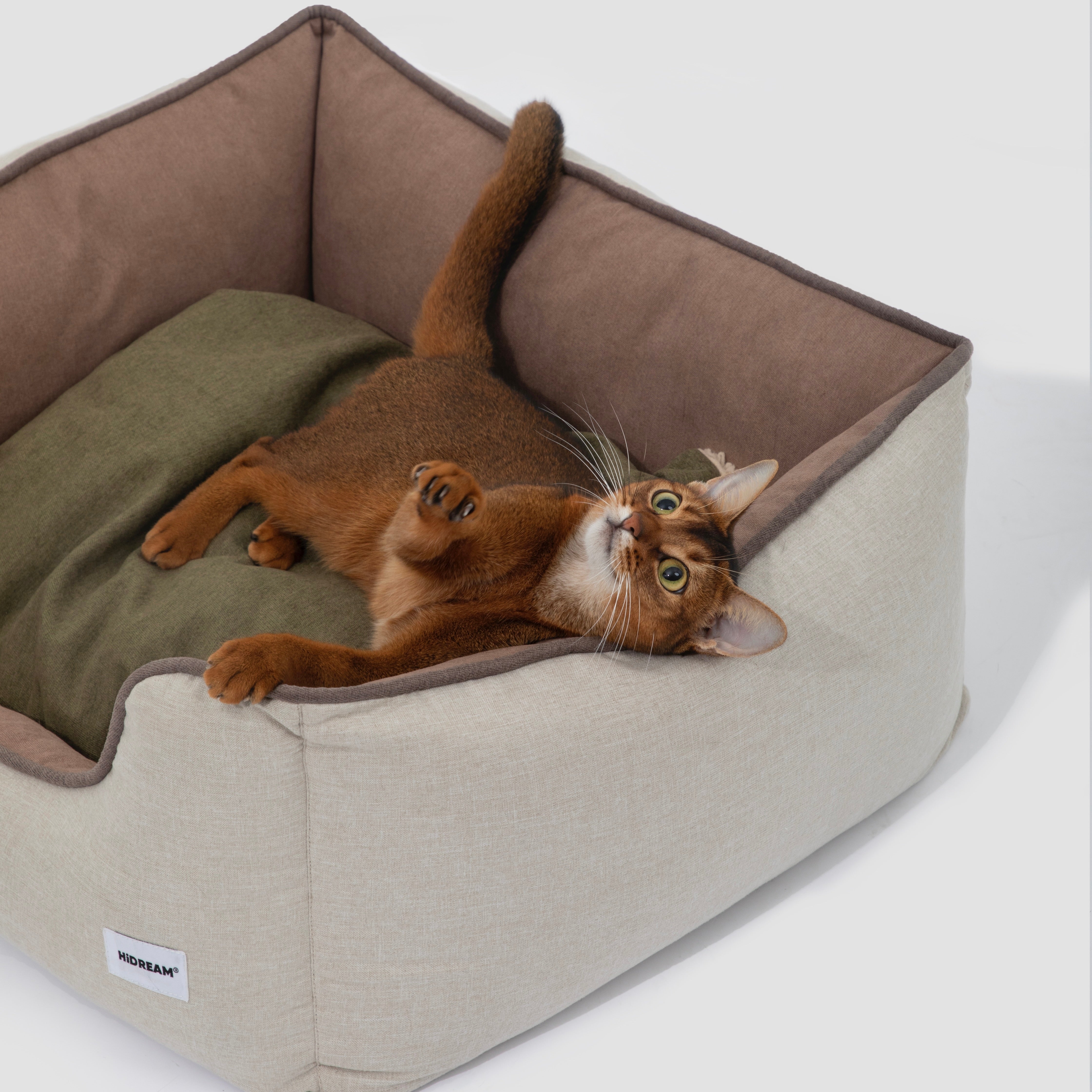 HiDREAM Four-Season Pet Bed shown with playful cat lying on reversible green cushion. Cozy, washable nest for cats and small dogs.
