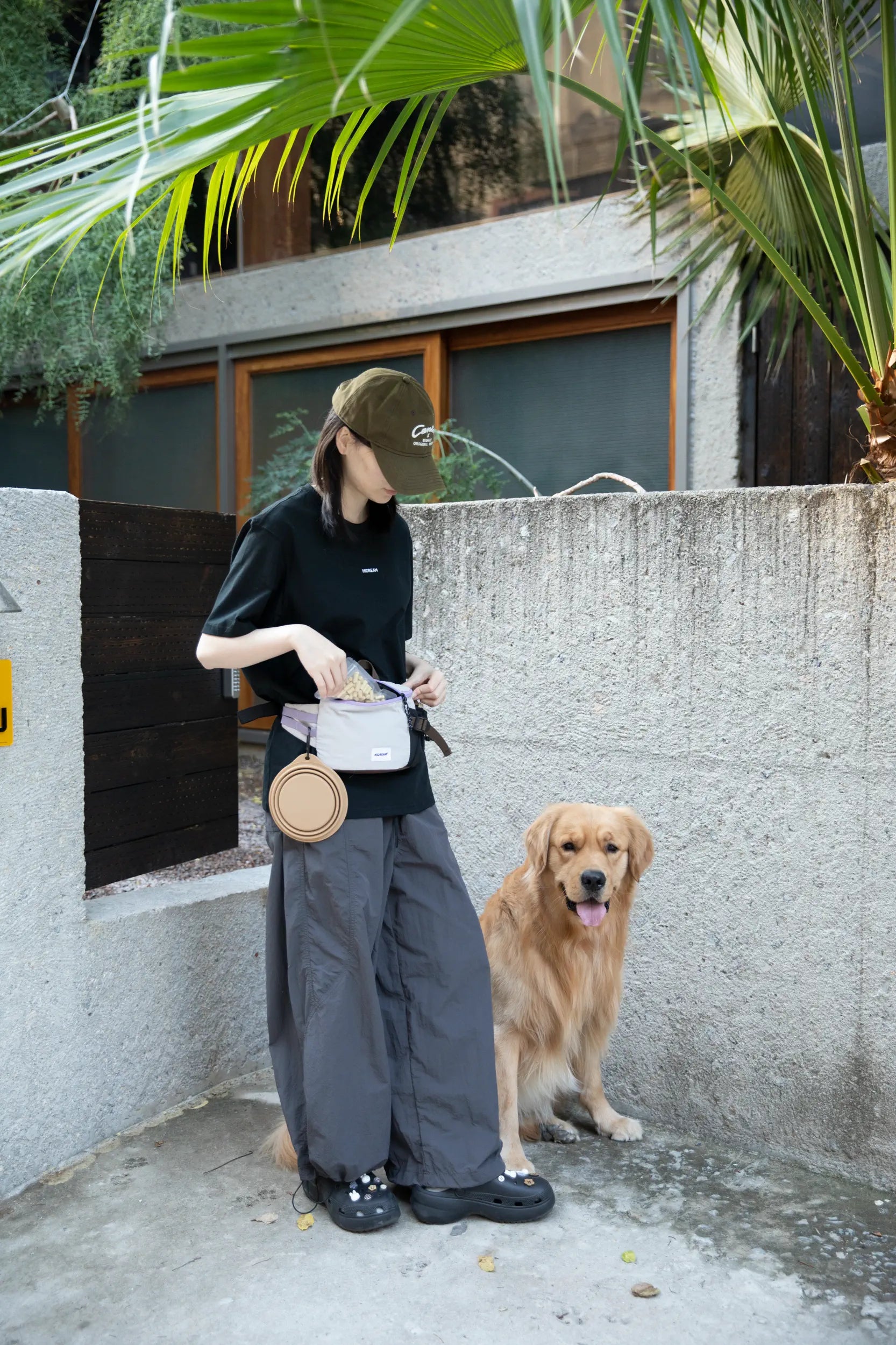 Dog trainer wearing a HiDREAM treat pouch beside a Golden Retriever