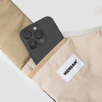 Smartphone in outer pocket of beige HiDREAM Crossbody Travel Bag for Pets, demonstrating added storage for essentials.