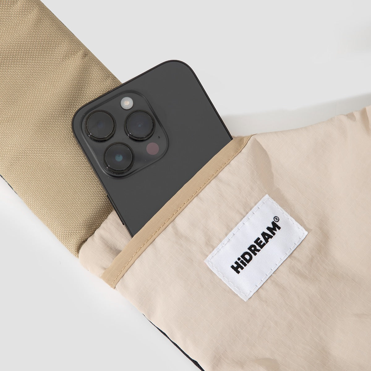 Smartphone in outer pocket of beige HiDREAM Crossbody Travel Bag for Pets, demonstrating added storage for essentials.