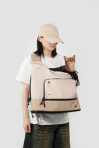 Woman carrying a cat in beige HiDREAM Crossbody Travel Bag for Pets, breathable mesh top and secure drawstring closure visible.