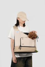 Woman placing a small dog into beige HiDREAM Crossbody Travel Bag for Pets, demonstrating secure and comfortable pet entry.