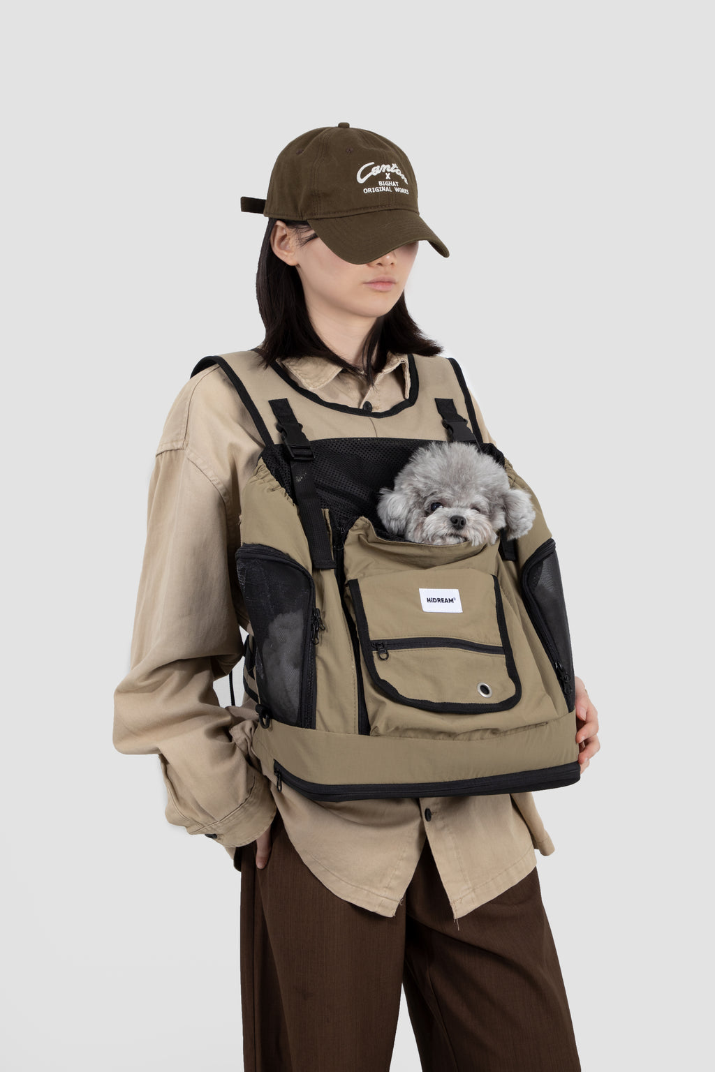 Woman wearing khaki HiDREAM Mountain Series Chest Pet Tote with small dog inside, showcasing ergonomic front-carry design.