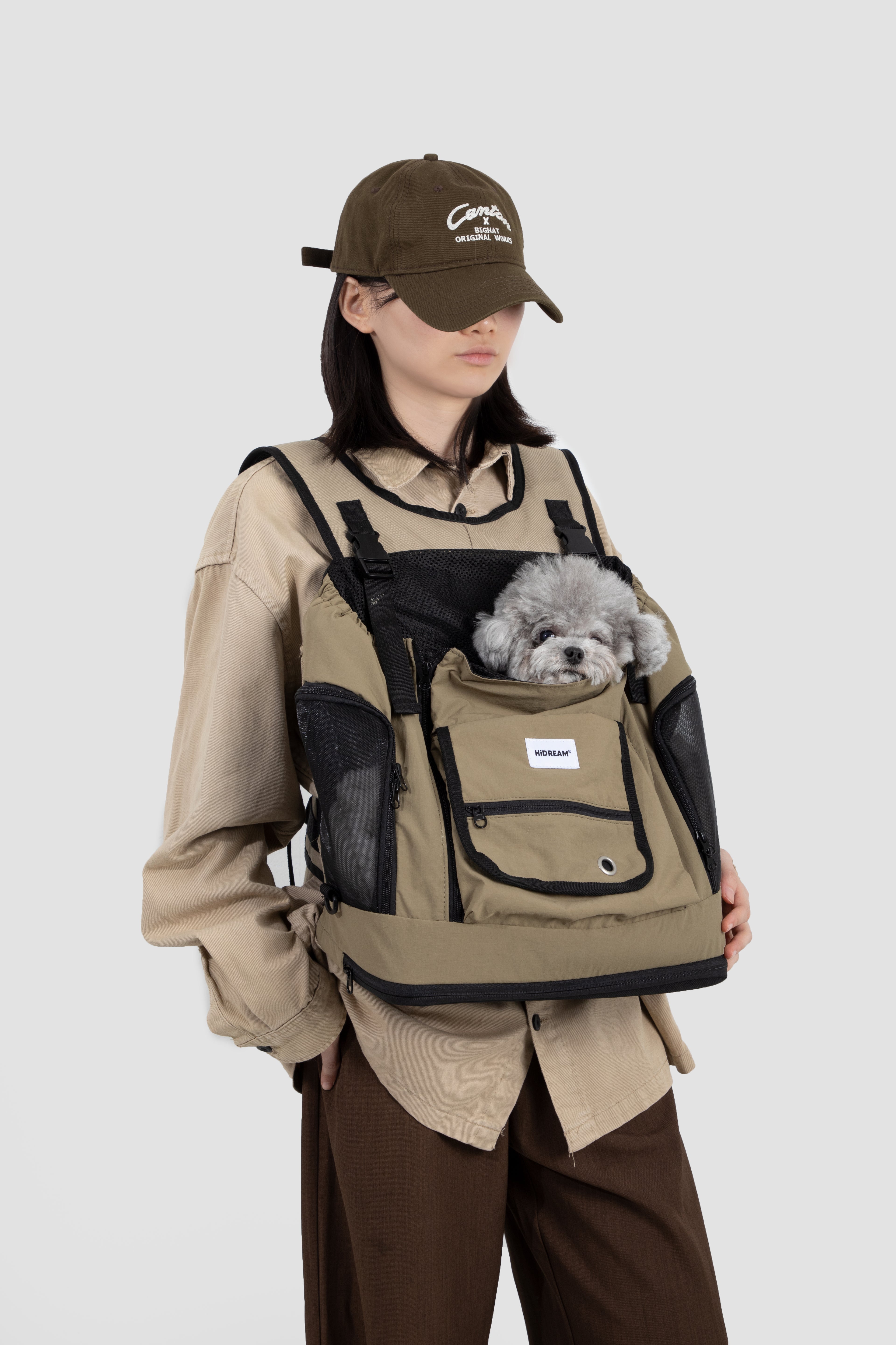 Woman wearing khaki HiDREAM Mountain Series Chest Pet Tote with small dog inside, showcasing ergonomic front-carry design.