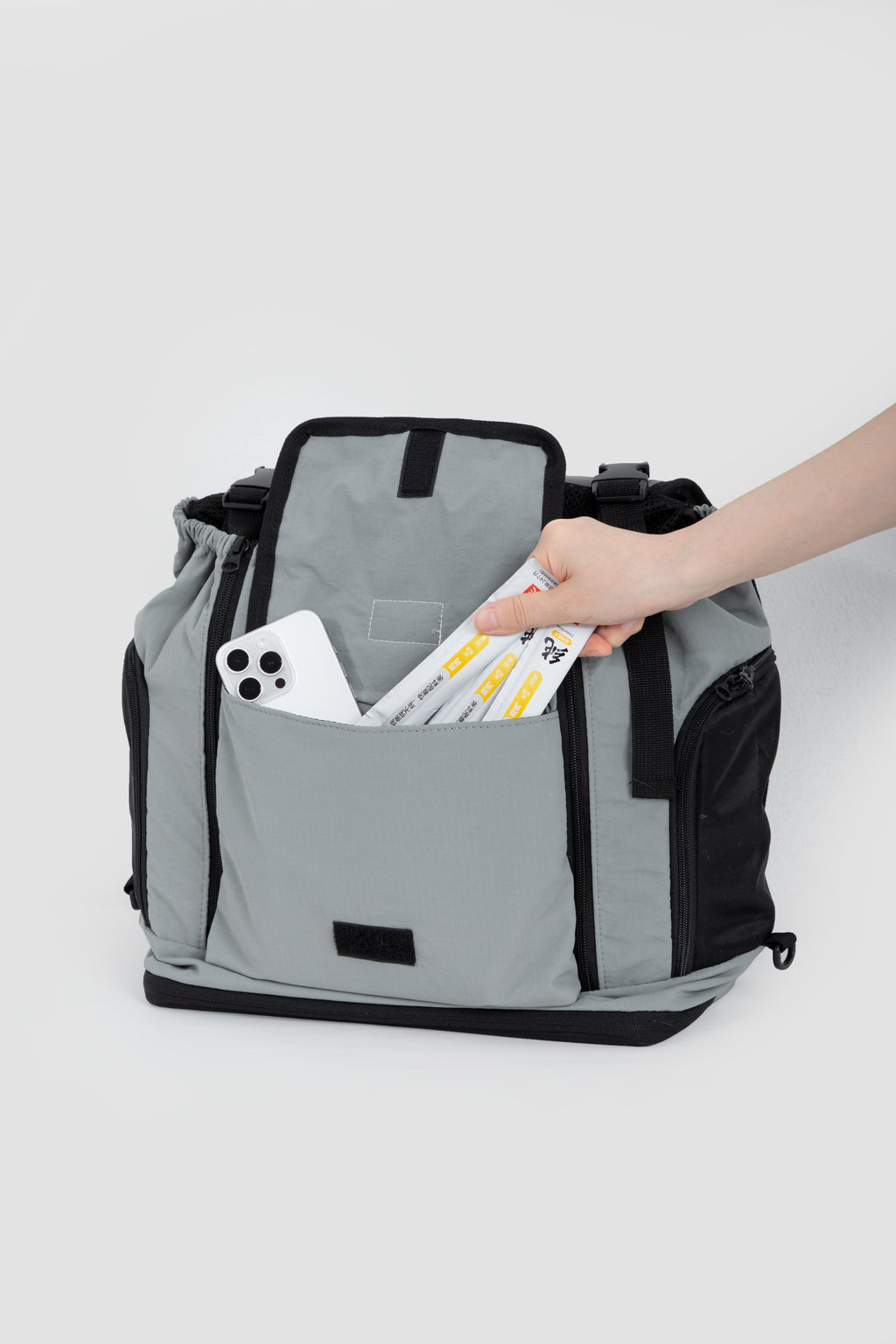 Front storage pocket of HiDREAM Mountain Series Chest Pet Tote holding phone and pet treats, highlighting practical design.