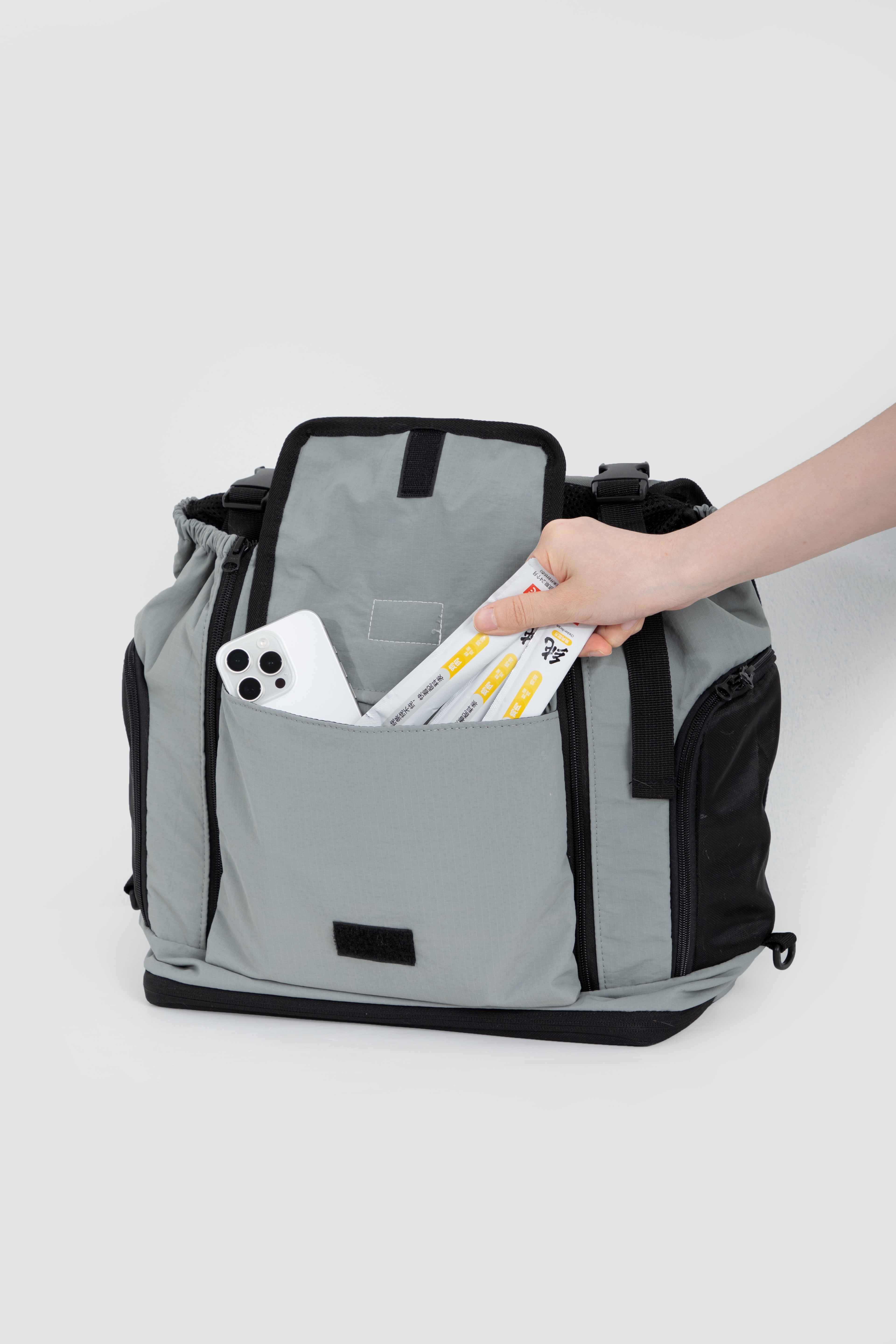 Front storage pocket of HiDREAM Mountain Series Chest Pet Tote holding phone and pet treats, highlighting practical design.