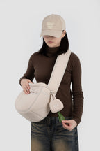 Woman wearing crossbody bag with HiDREAM Dog Poop Bag Holder clipped on, demonstrating hands-free convenience.