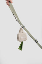 Beige HiDREAM Dog Poop Bag Holder clipped to green leash, dispensing waste bags for convenient dog walking.