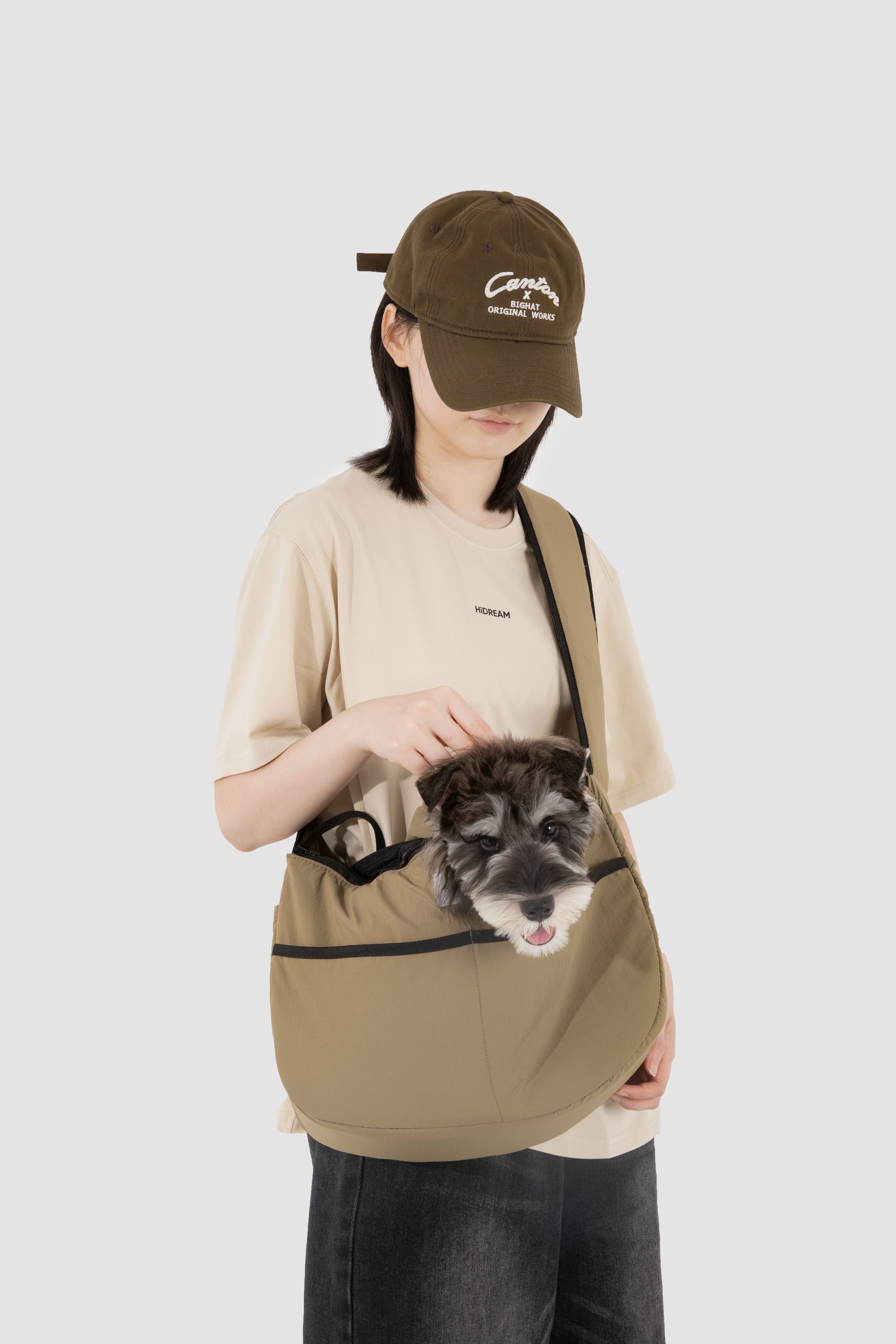 Woman carrying a dog in the khaki HiDREAM Crossbody Pet Carrier Tote. Comfortable and secure for small pets during walks or errands.
