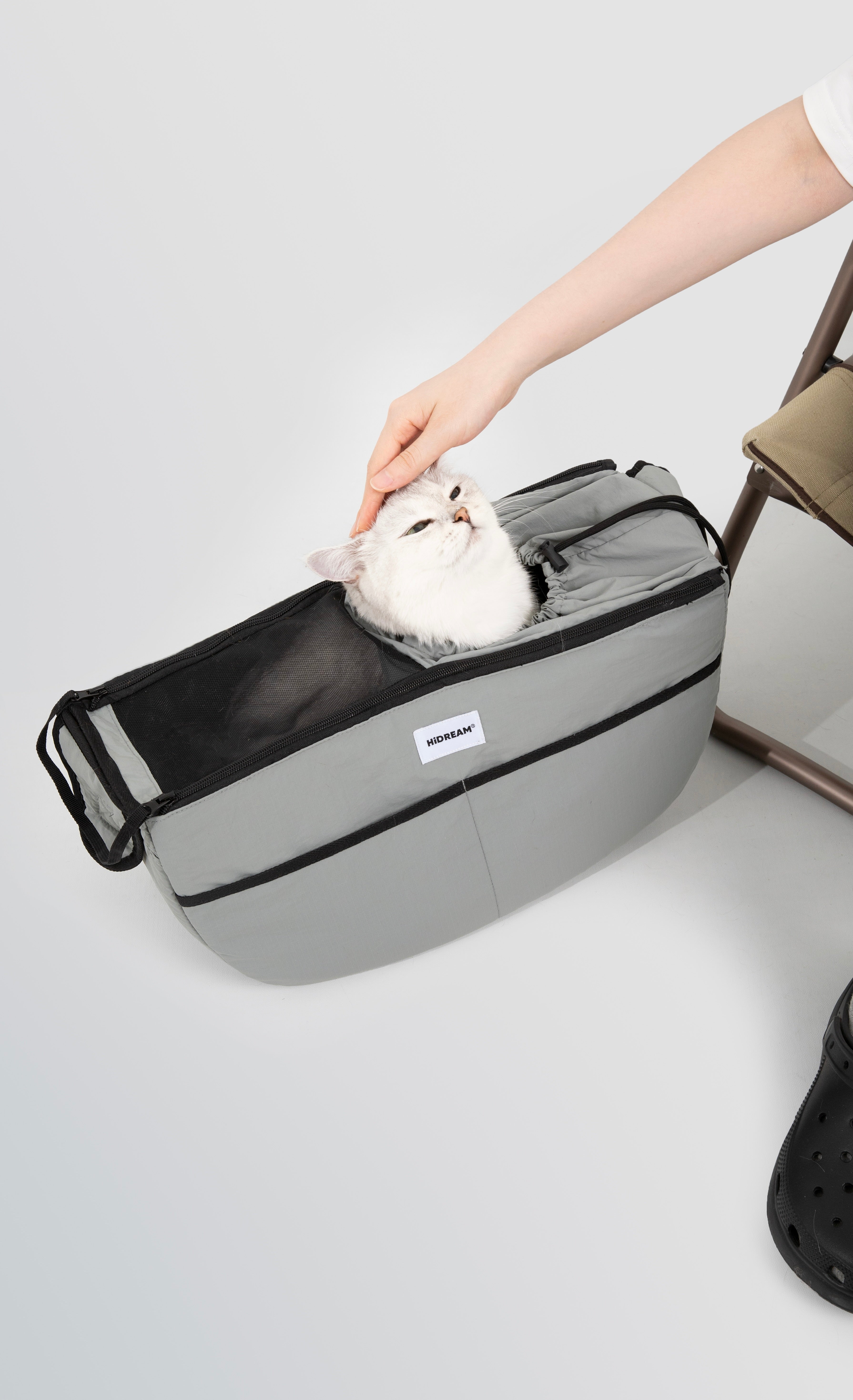 White cat resting in grey HiDREAM Crossbody Pet Carrier Tote placed on the floor. Soft interior and secure design for relaxed pet travel.