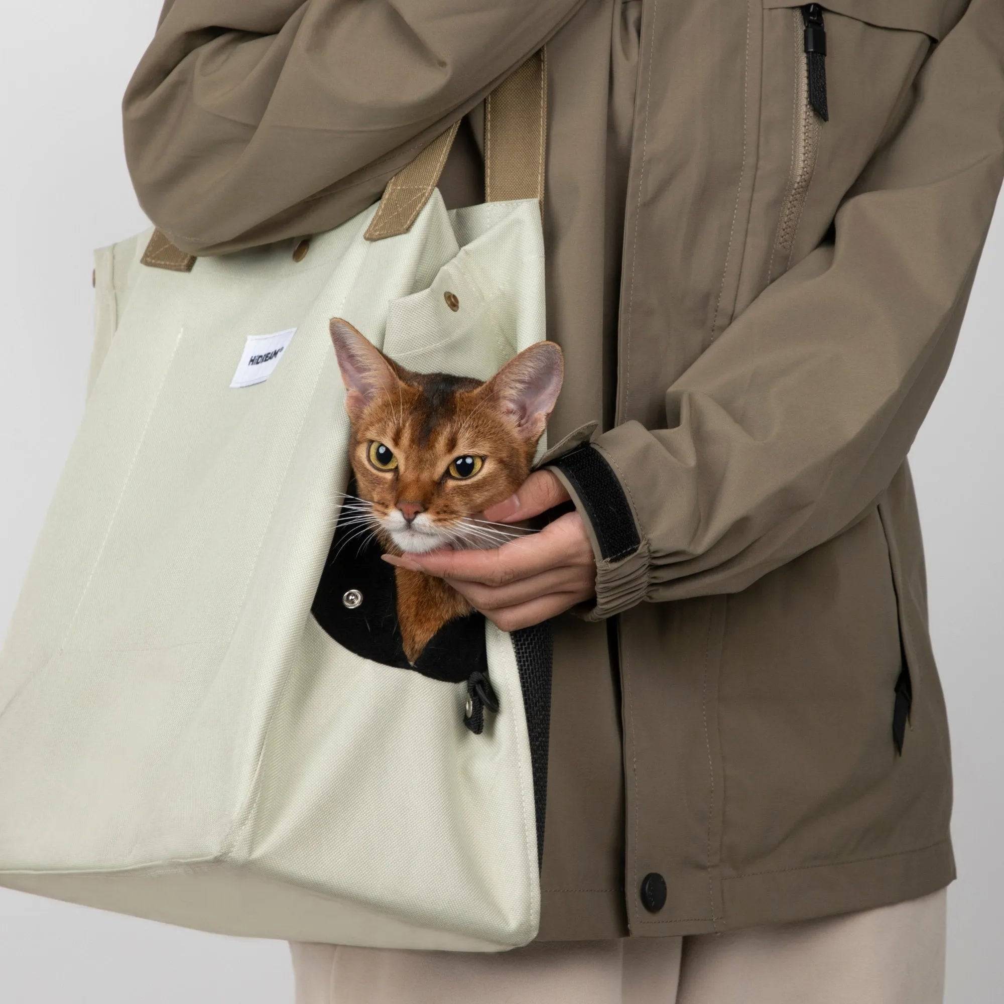 HiDREAM Padded Tote Bag in cream with a cat peeking from the side opening, highlighting its secure and cozy pet carrier features.