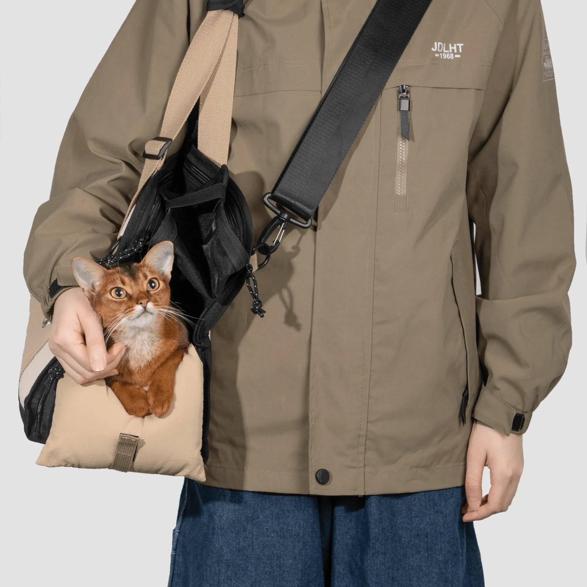 Cat peeking from side opening of HiDREAM Sling Pet Carrier worn over shoulder. A stylish 3-in-1 papoose bag for hands-free pet travel in Australia.