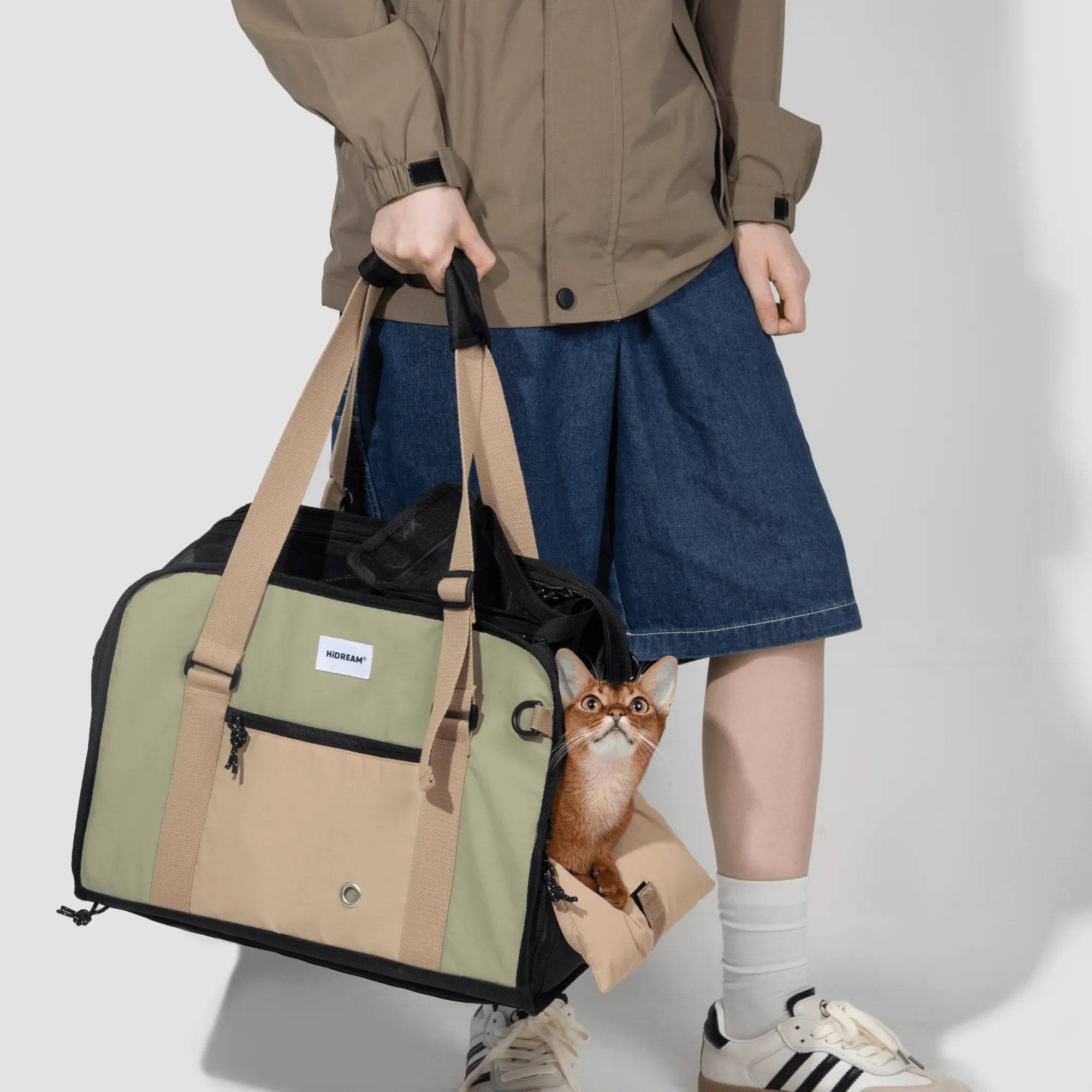 Cat peeking from side of green HiDREAM Sling Pet Carrier held by owner. A 3-in-1 semi-open papoose bag for stylish pet travel in Australia.